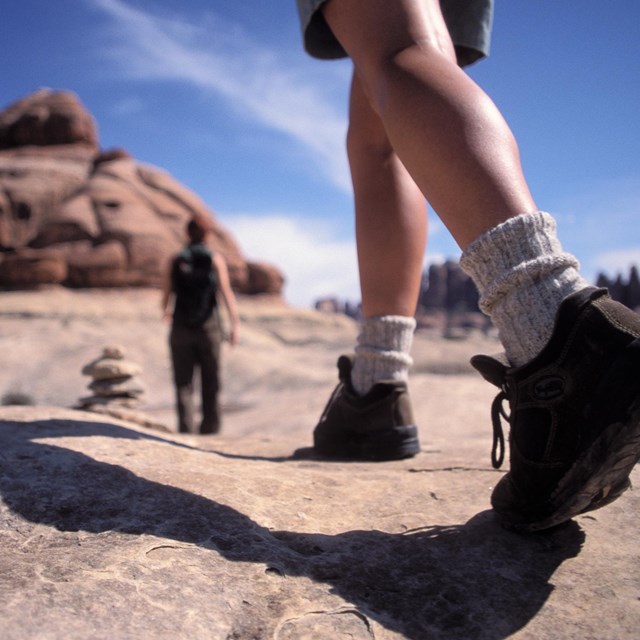 a close up a person's legs and hiking boots on a trail