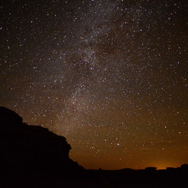 a star-filled sky over silhouetted rock formations