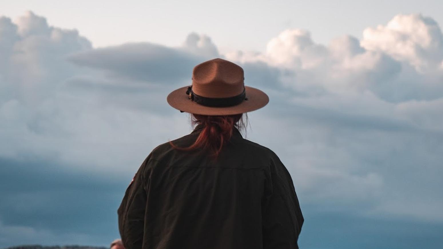 A uniformed ranger stands before a late sunset
