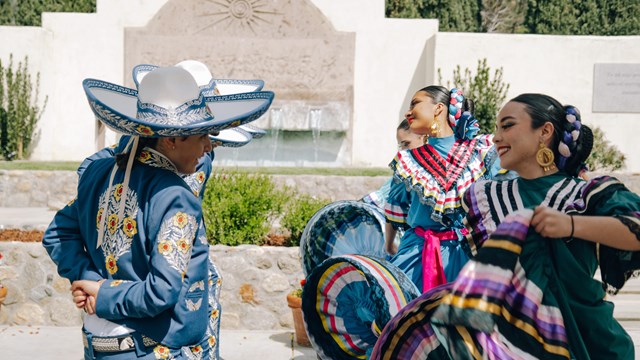 Dancers perform in front of a large water fountain.