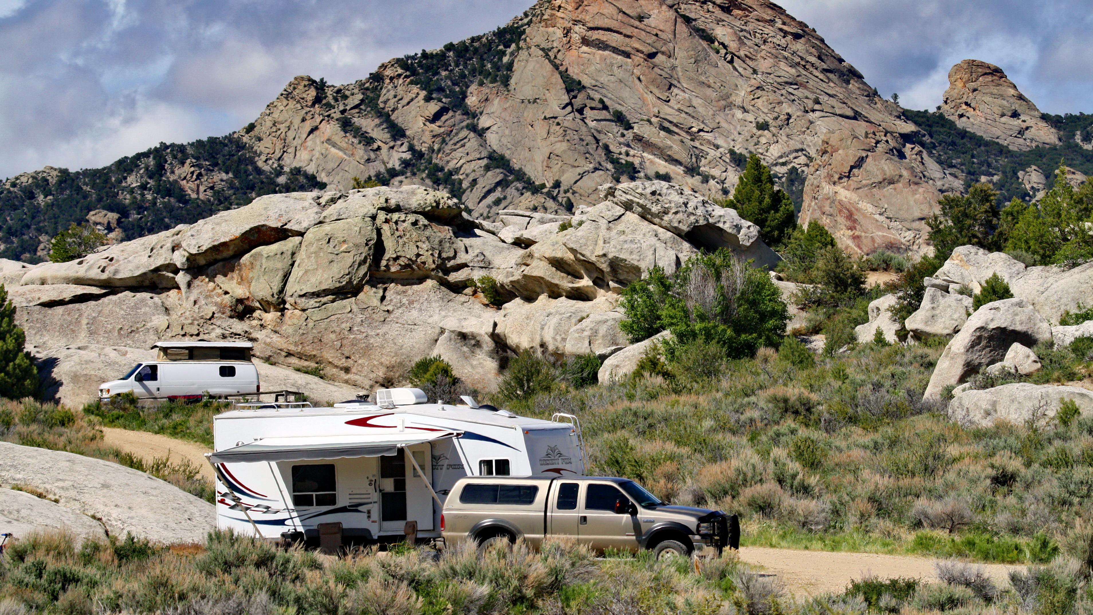 A truck with a camper driving through the City of Rocks.