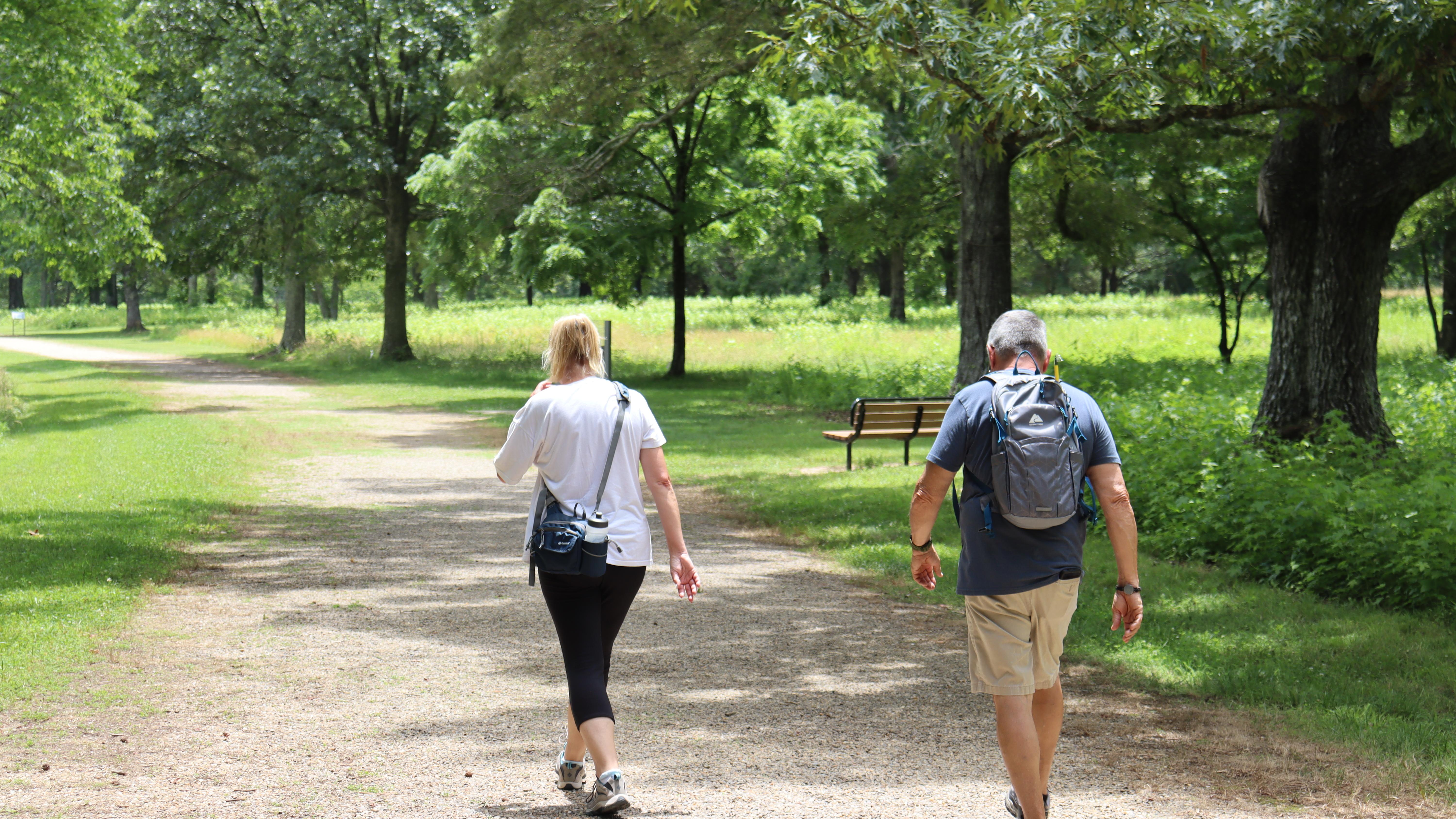 Two visitors walk down a dirt road