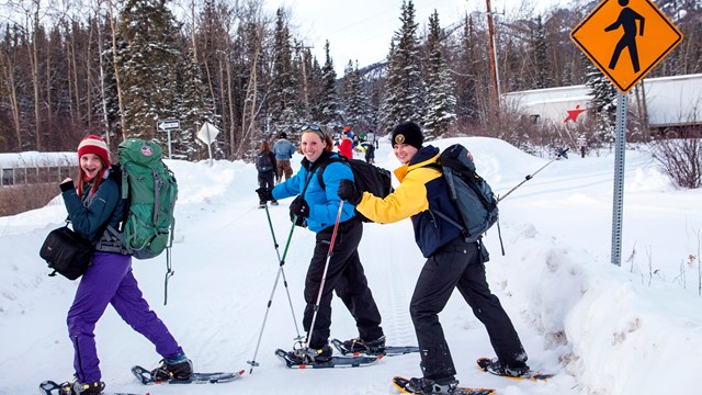 Snowshoers walking past a hikers road sign