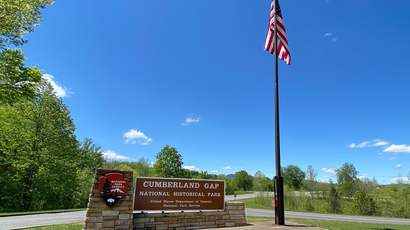 Park welcome sign with an American flag standing next to it