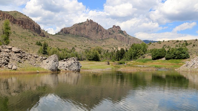Image of pinnacles and mesas reflected in a body of water along a shoreline