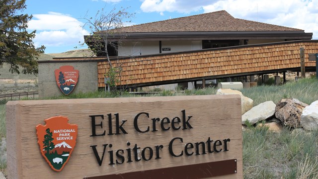 A visitor center building with a large sign 'Elk Creek Visitor Center' and a NPS arrowhead