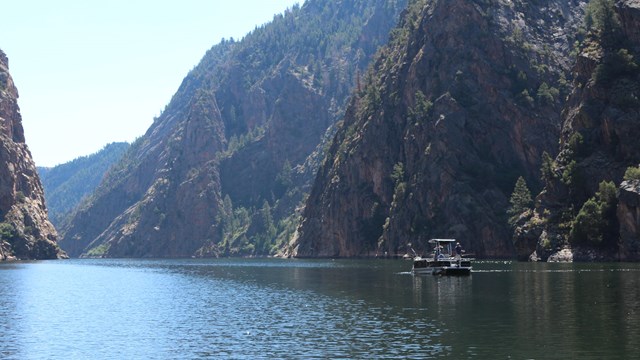 A small fishing boat on a reservoir between steep canyon walls