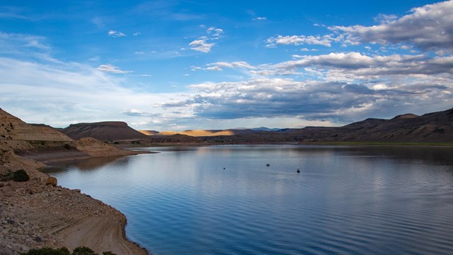 A blue reservoir with small boats on the horizon