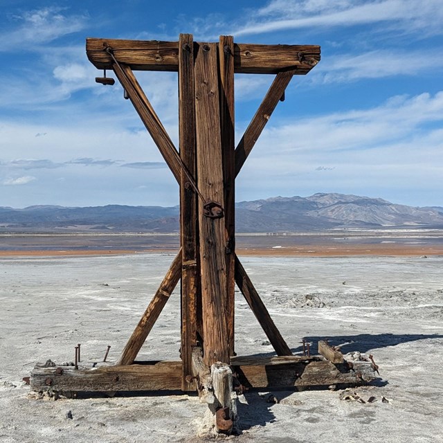 historic wooden structure in a white salt valley surrounded by desert mountains.