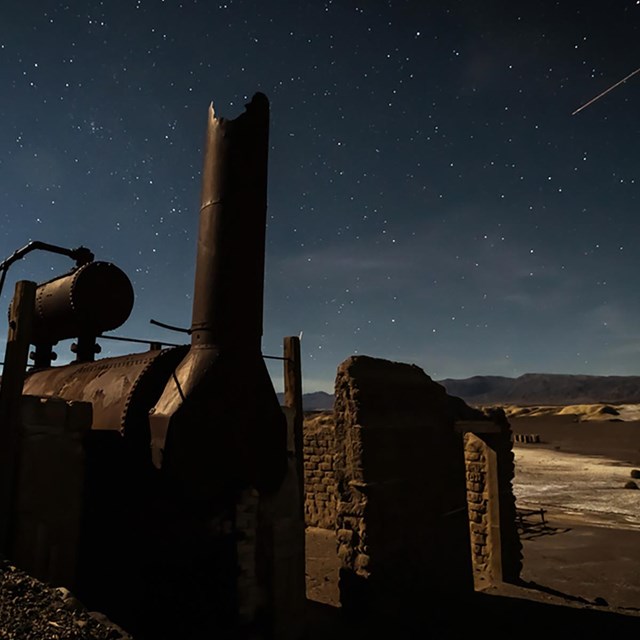 Stone walls around a metal furnace under a starry sky.