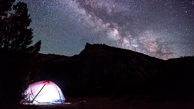 lighted tent underneath a starr filled night sky