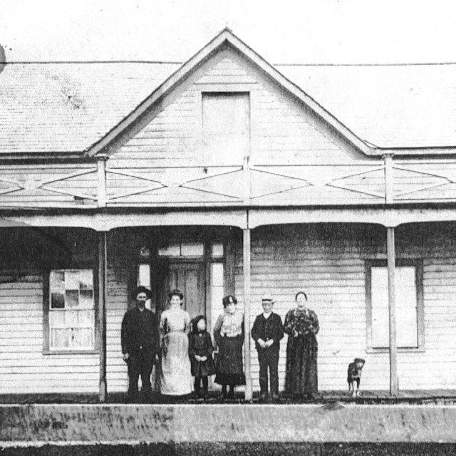 Family and dog on front porch of historic farmhouse.