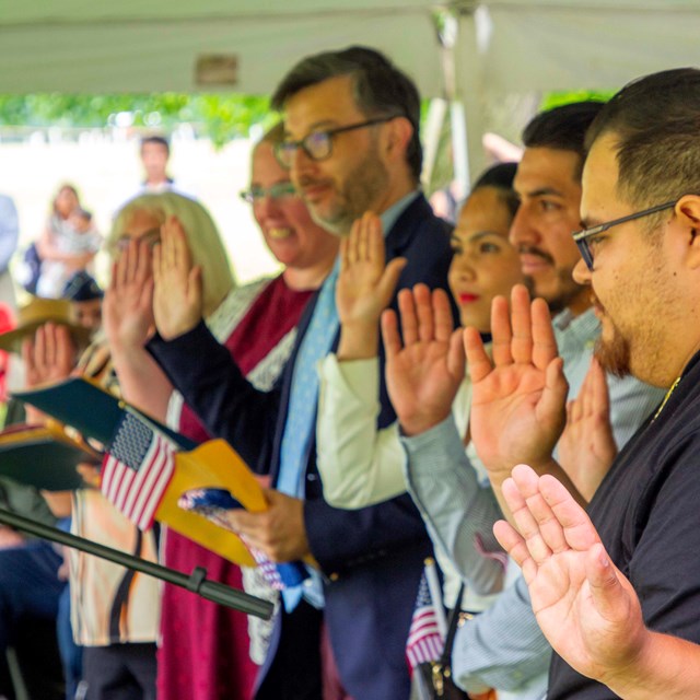 New citizens raise their hands and hold American flags