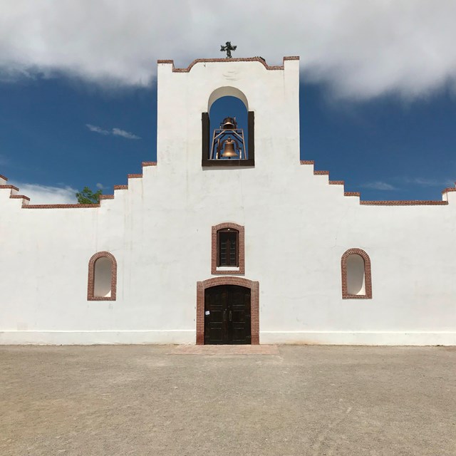 A white, spanish-style mission, under a blue sky.
