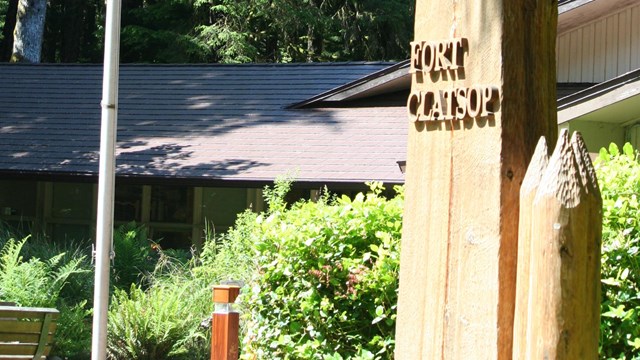 La entrada del centro de visitantes con un monumento de madera con las palabras Fort Clatsop