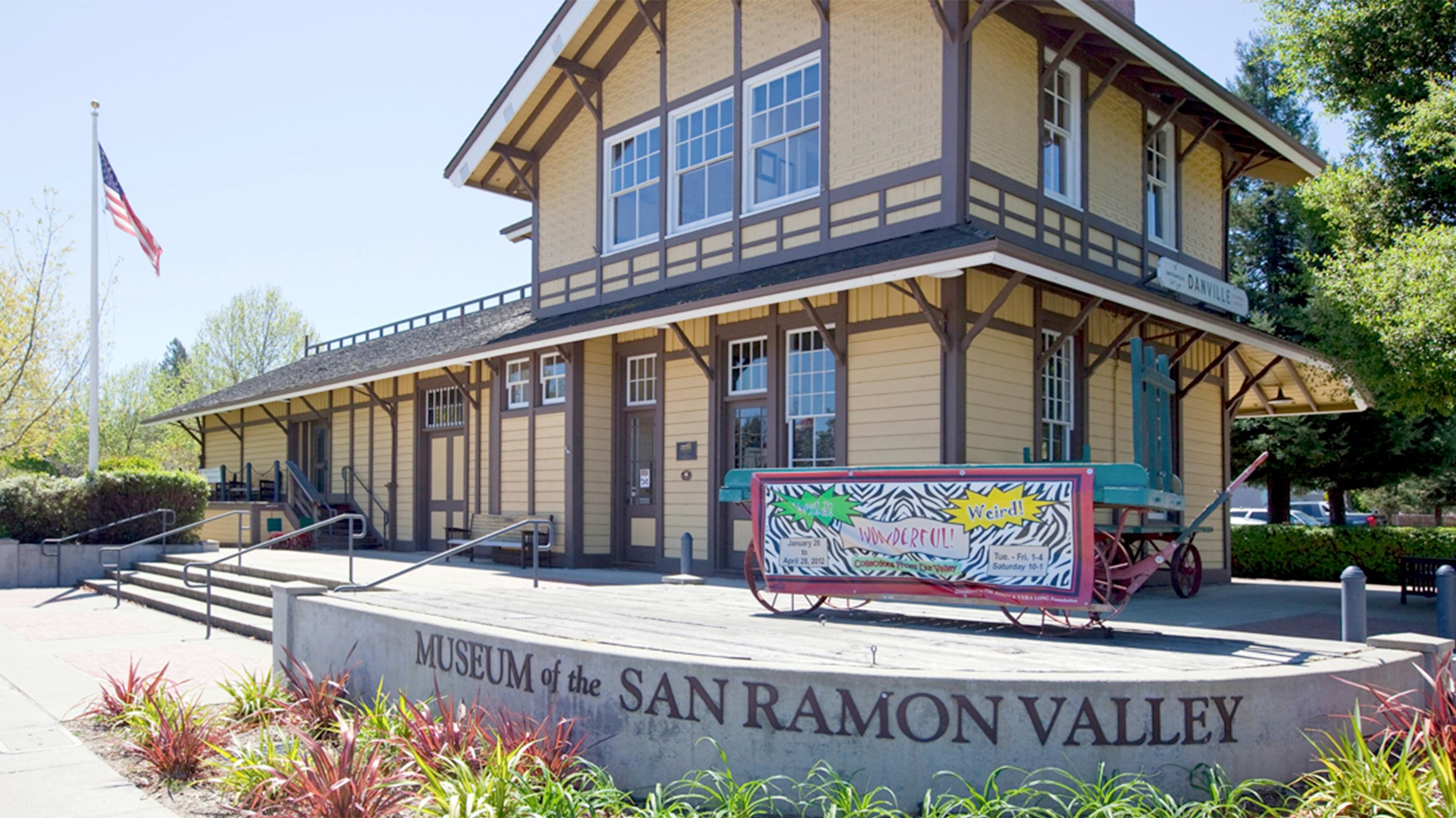 Historic yellow building with brown trim, labeled Museum of the San Ramon Valley, and wagon.