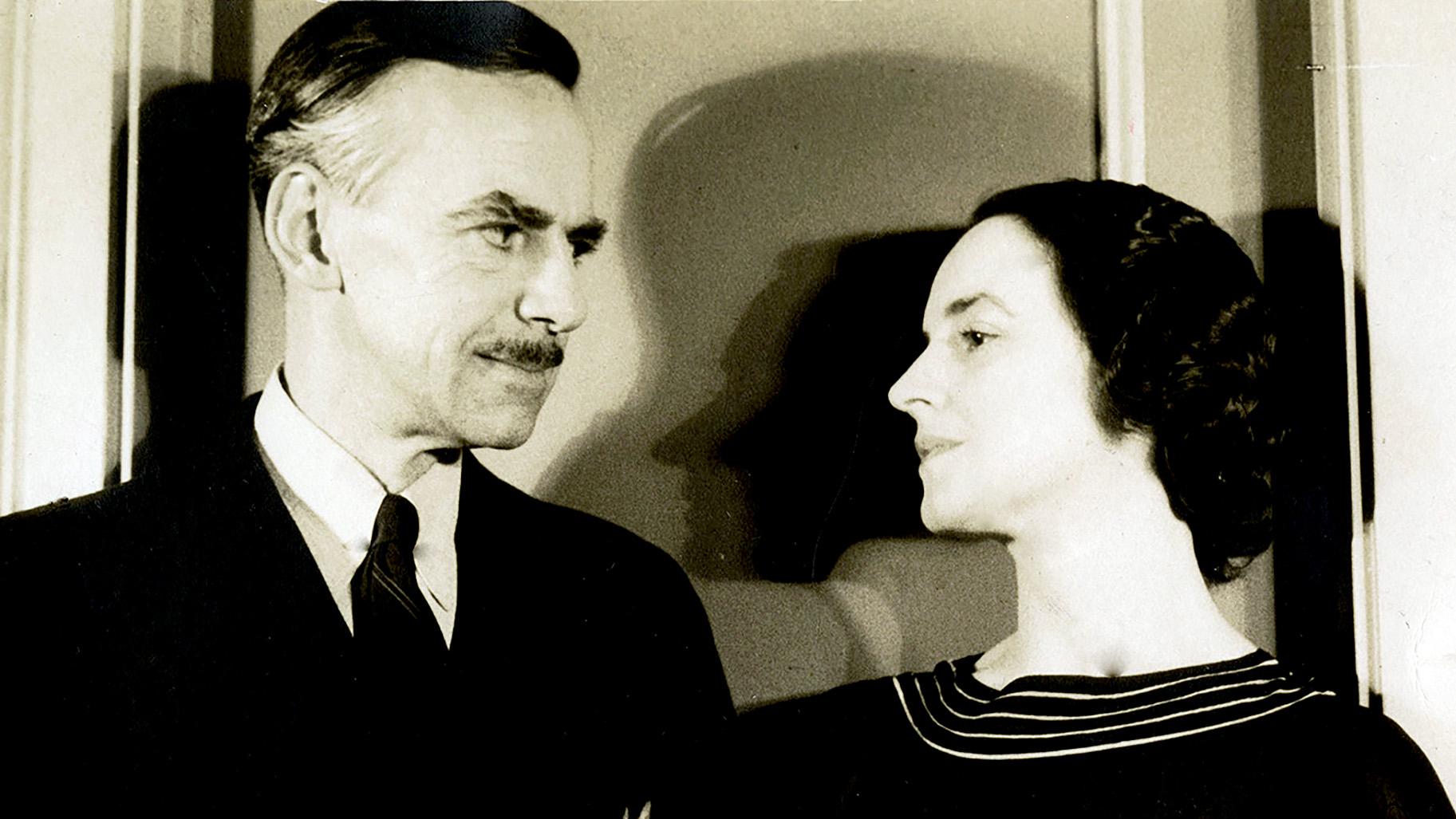 Vintage photo of a man in a suit and tie gazing at a woman in a striped-collar dress.