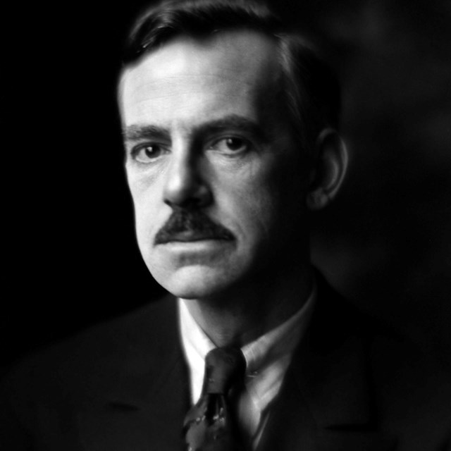 A portrait of Eugene O'Neill, an American playwright, dressed in a dark suit and tie.