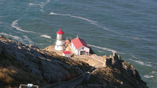 lighthouse down a rocky mountain with water