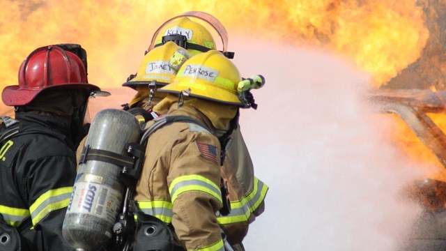 structural firefighters suppressing a vehicle fire in training