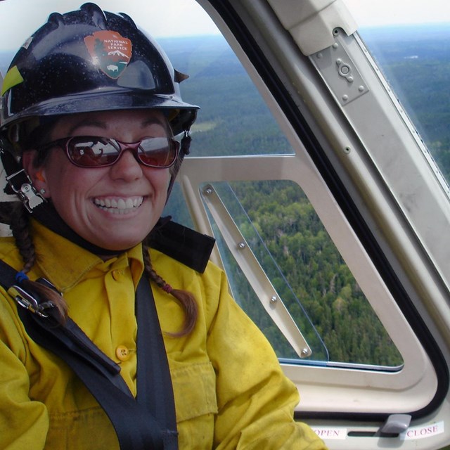 Firefighter smiling inside a helicopter flying over a national park