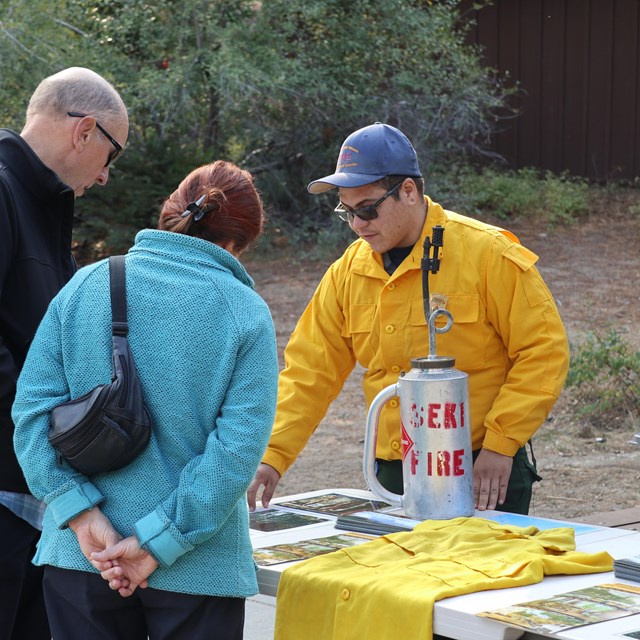 A fire information officer talks with two visitors about a prescribed burn.