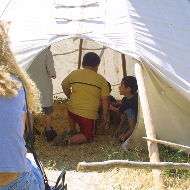 School group exploring the inside of a tipi.