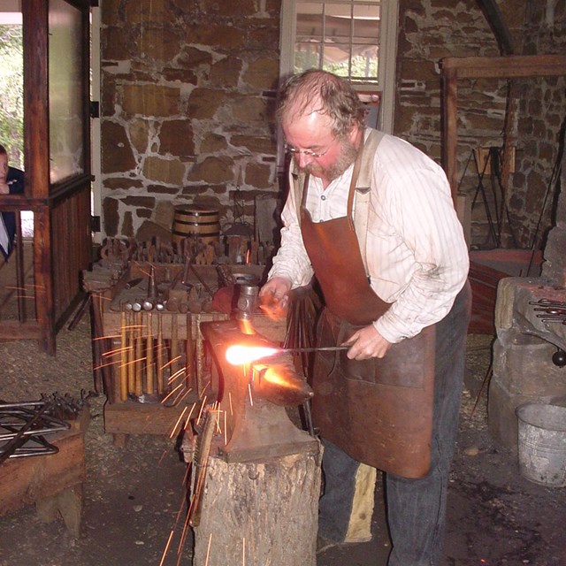 Blacksmith hammering hot iron on an anvil.