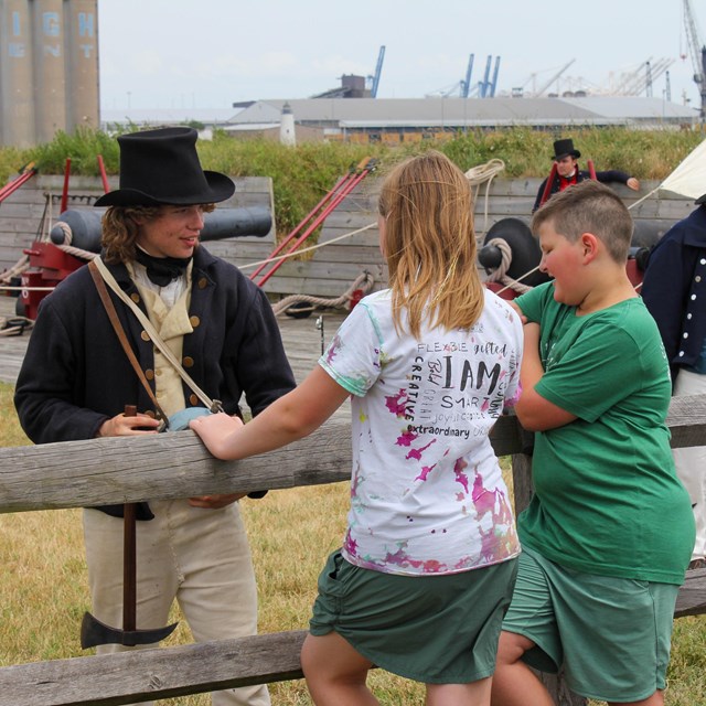 Fort McHenry Guard member talking with two young visitors. 
