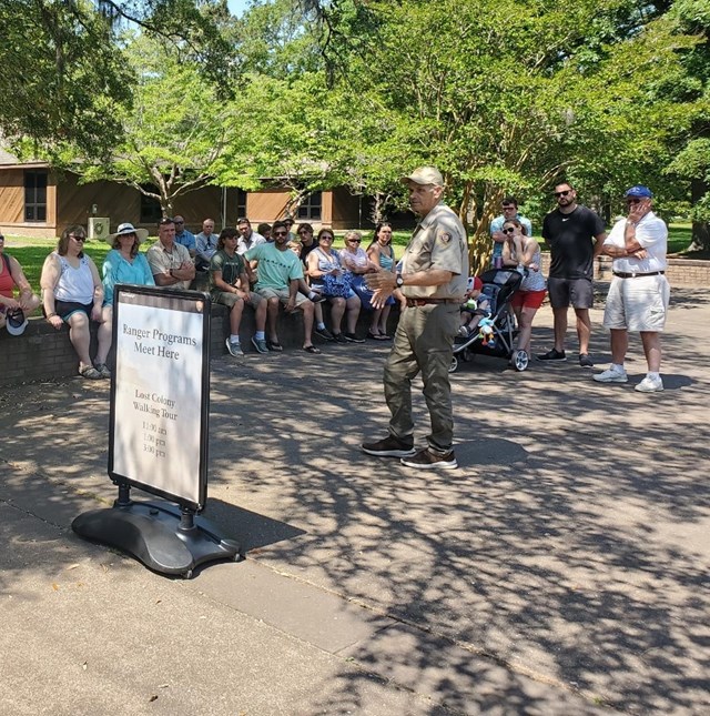 Two volunteers stand under shade tent as special event