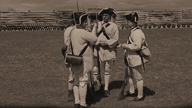 A black and white photo of three soldiers talking casually to each other.