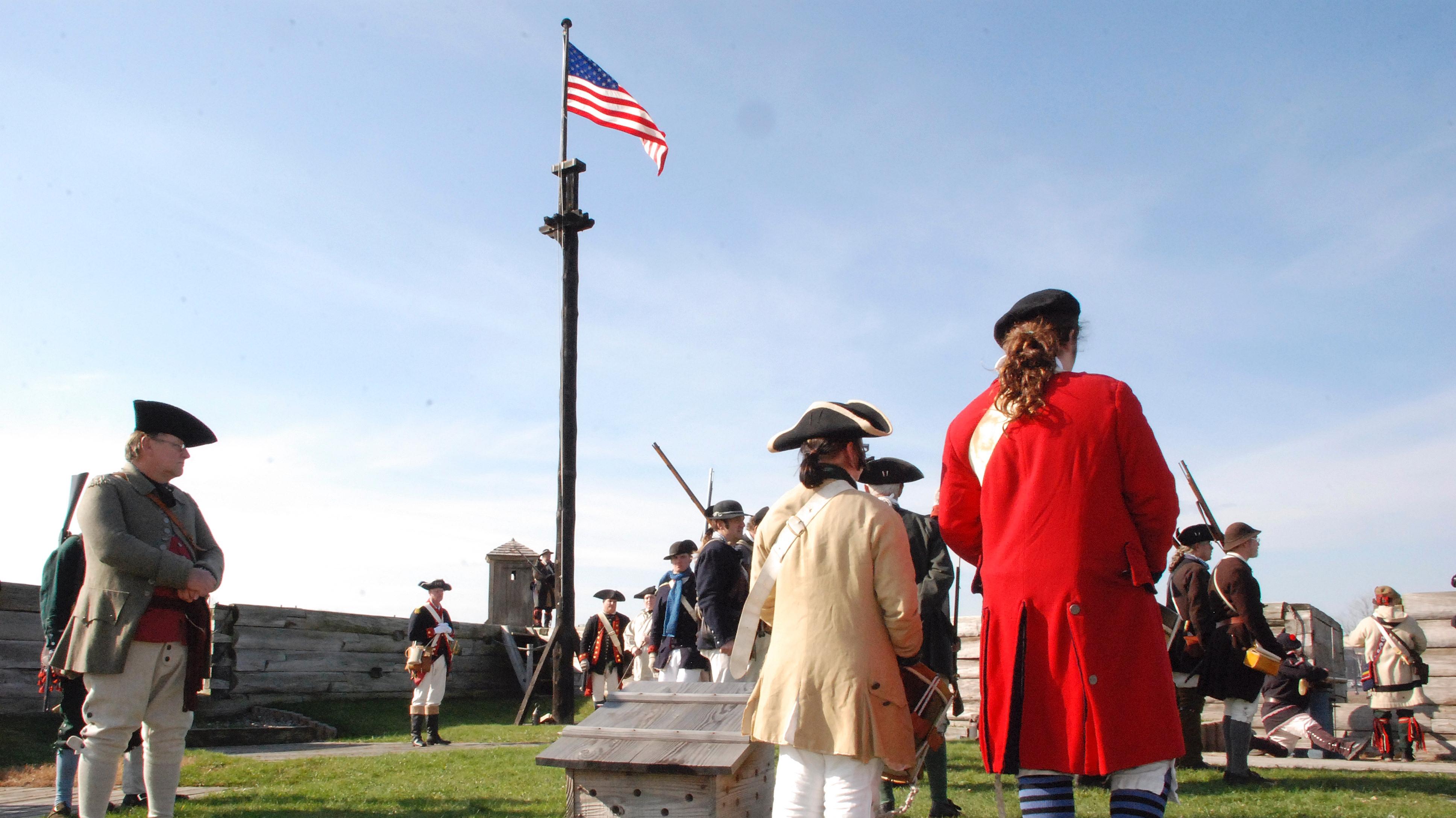 Soldiers stand saluting a flag.