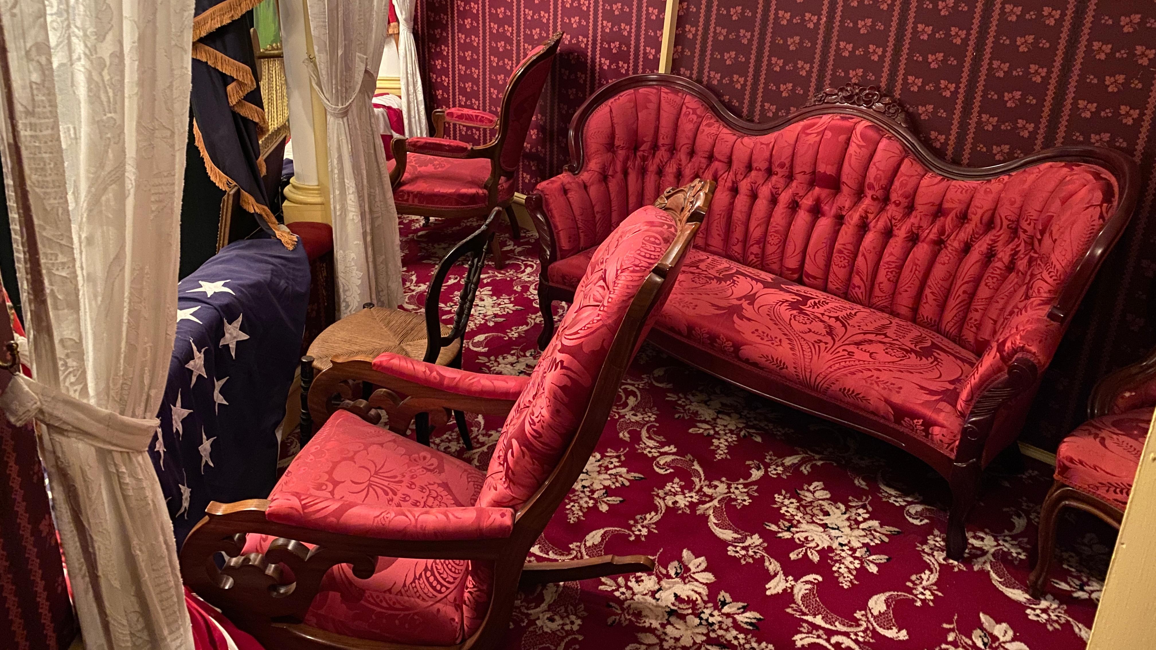 Theatre Box with red carpet, wallpaper, and red upholstered Victorian furniture.