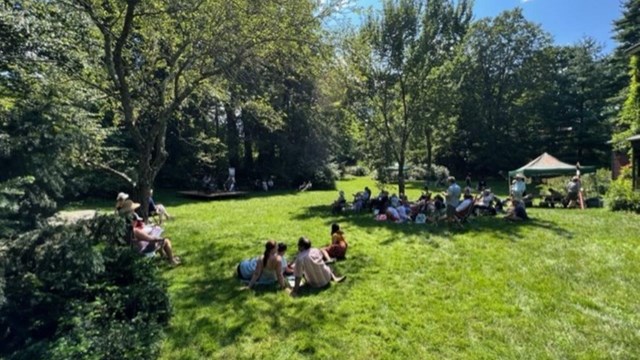 Group of people sit on green lawn grass
