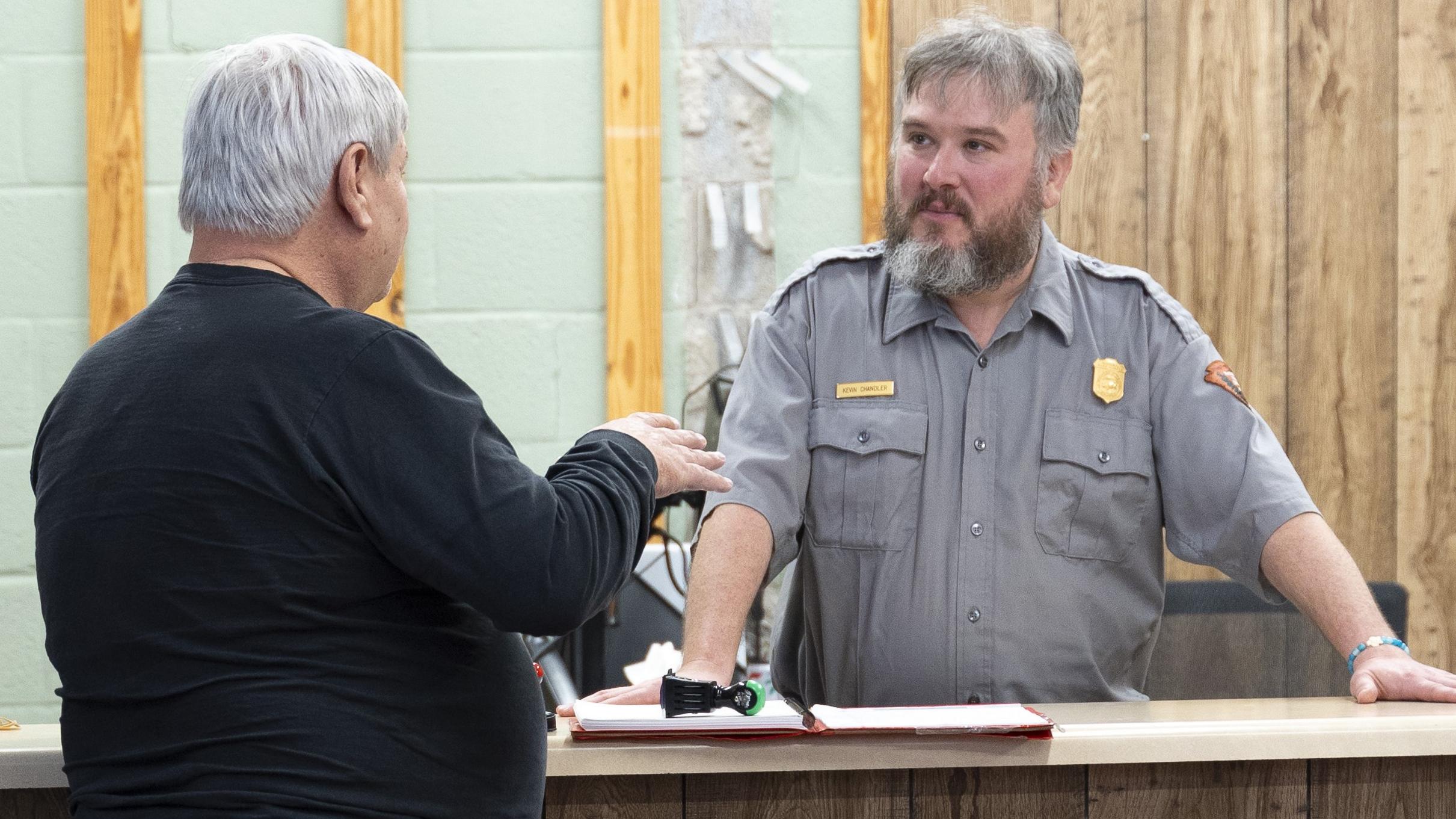 A ranger talking to a visitor at a visitor center desk.
