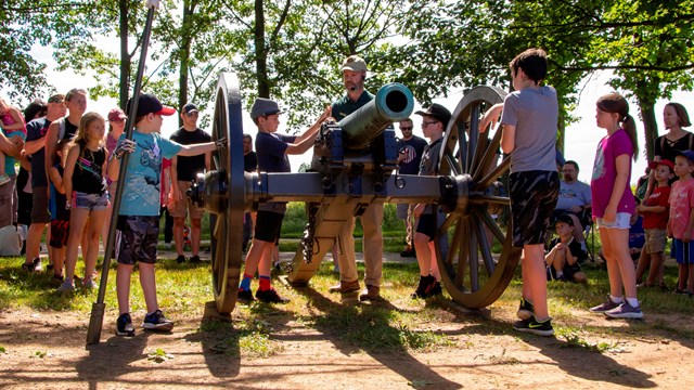 A park volunteer instructs children on the roles of Civil War artillery soldiers.