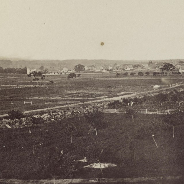 Black and white historical photograph of a wide field scattered with monuments.