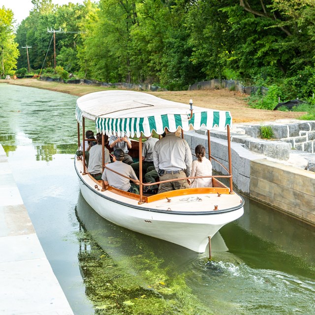 A small boat with a green and white striped tarp in a canal. 