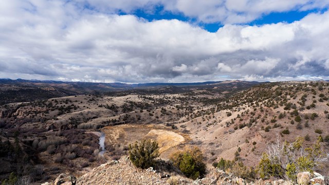 he scene showcases a rugged terrain of rolling hills covered with sparse vegetation.