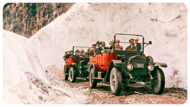 two red buses drive through deep snow with people in back