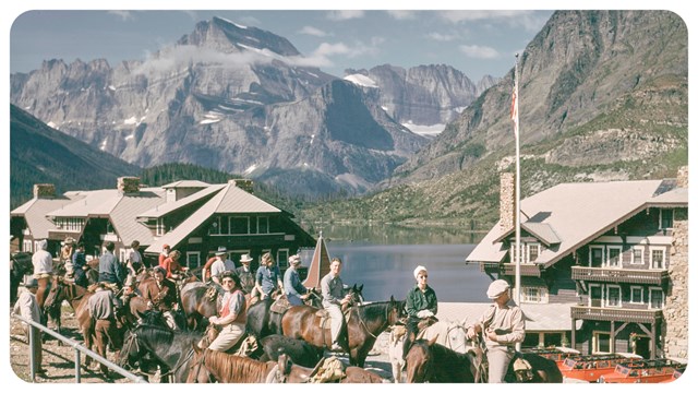 A small group of people sit on a hill with a mountain peak in the background. 