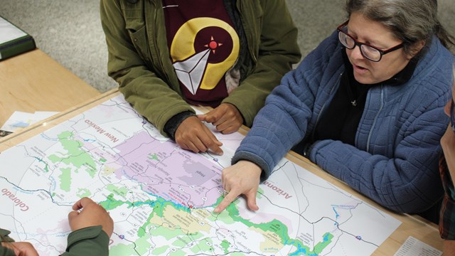 Two women point to Glen Canyon area map on visitor center desk