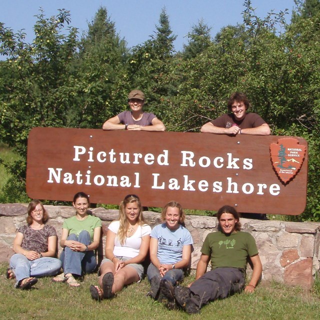 Staff members in front of park sign