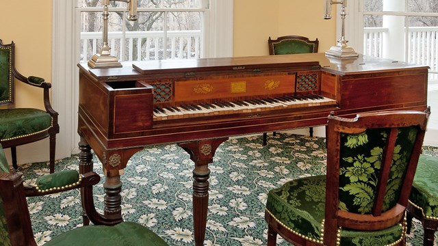 An early model piano among green silk upholstered 19th century chairs. 