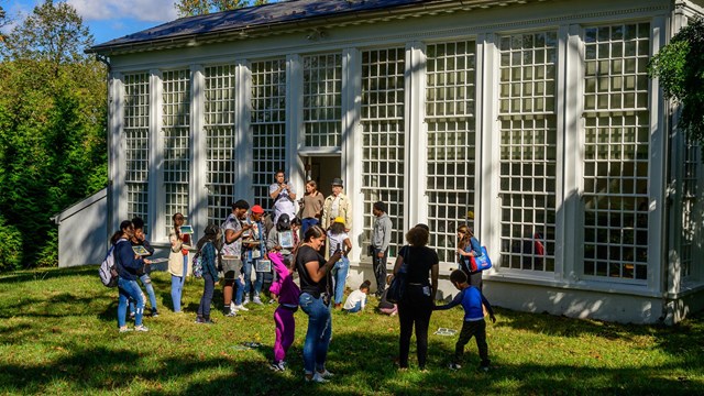A group of diverse people outside of the Orangery building, similar to a greenhouse.