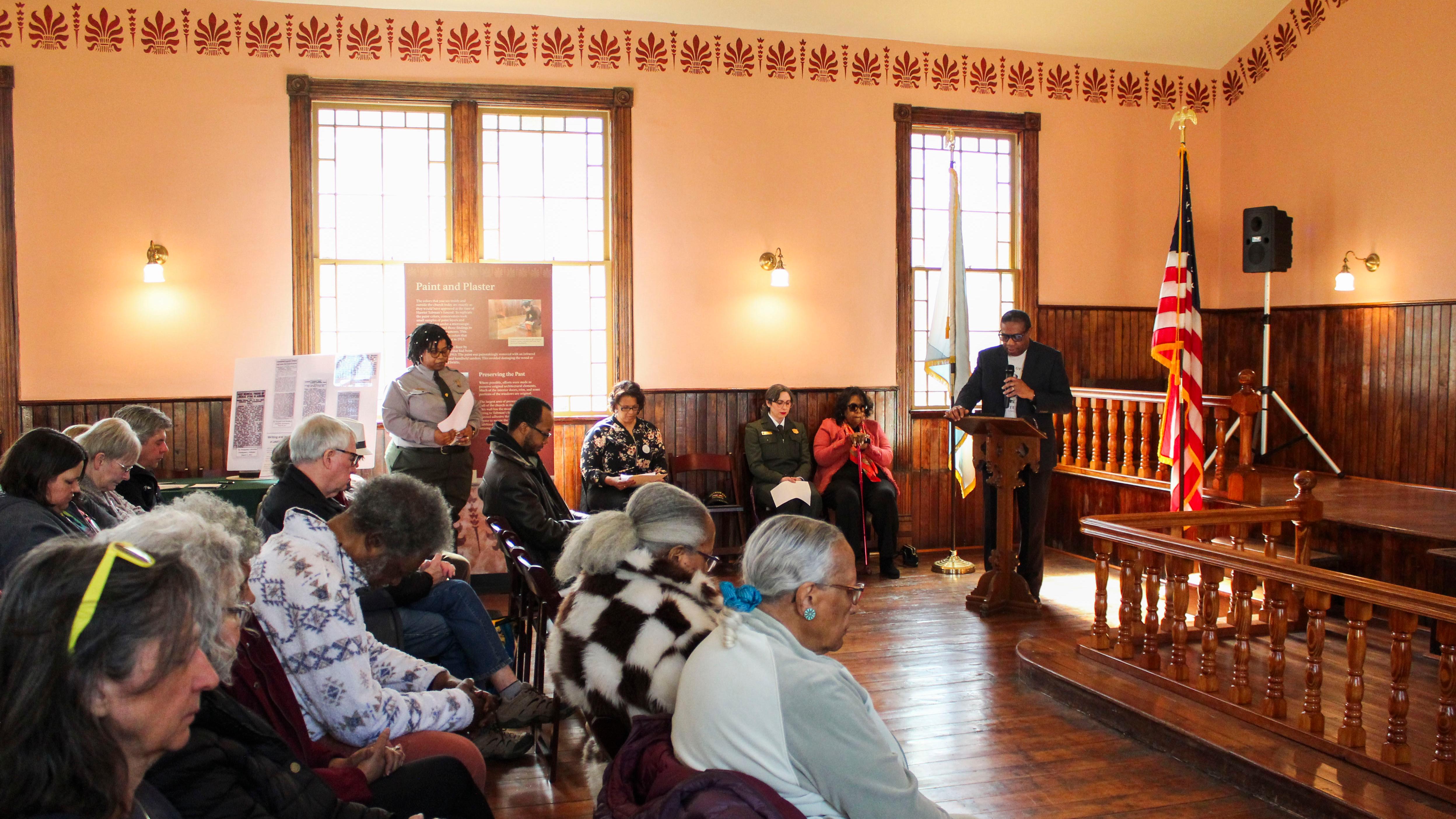A room full of people watching a man speak.