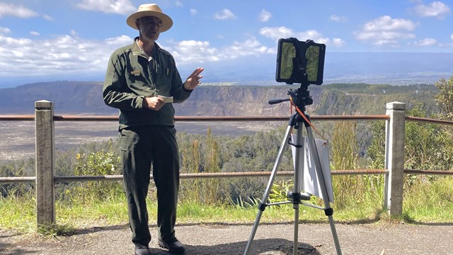 A ranger standing at an overlook providing a digital education program with an iPad.