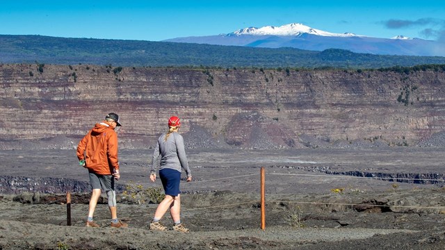 Two hikers on a road with a distant snow-covered mountain