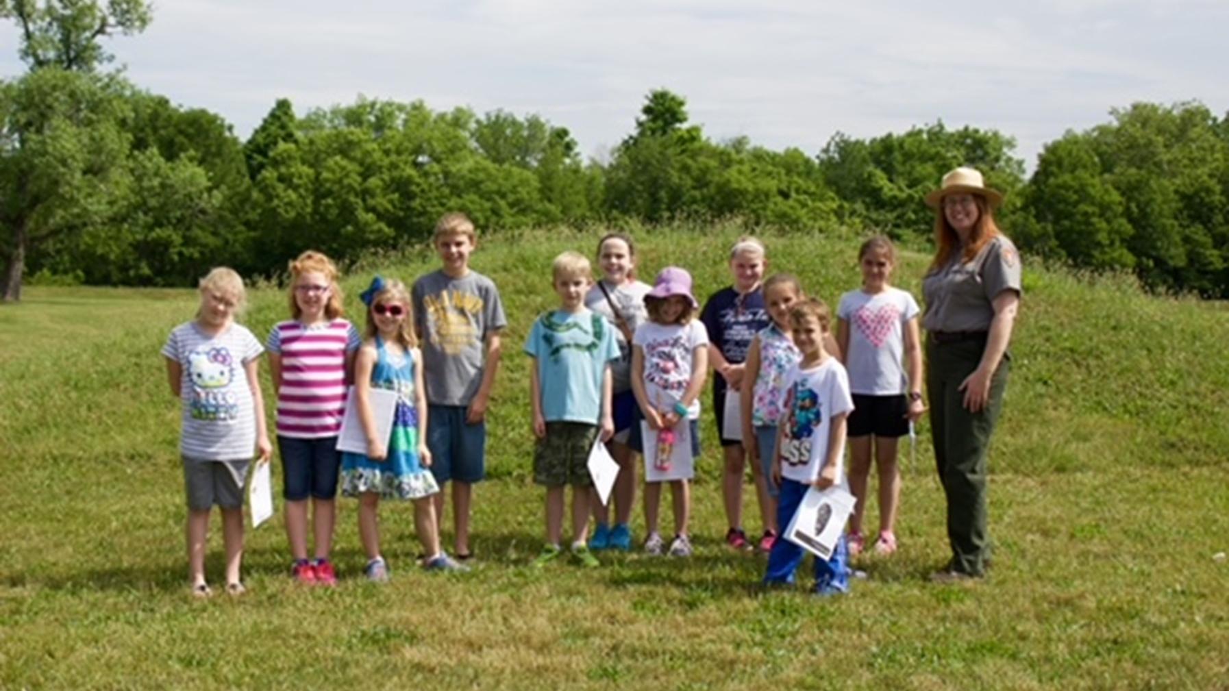 a group of children pose with a park ranger.