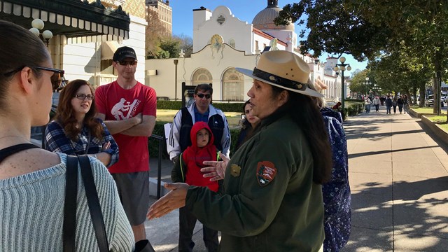 A park ranger speaks to visitors on a guided tour of a historic bathhouse